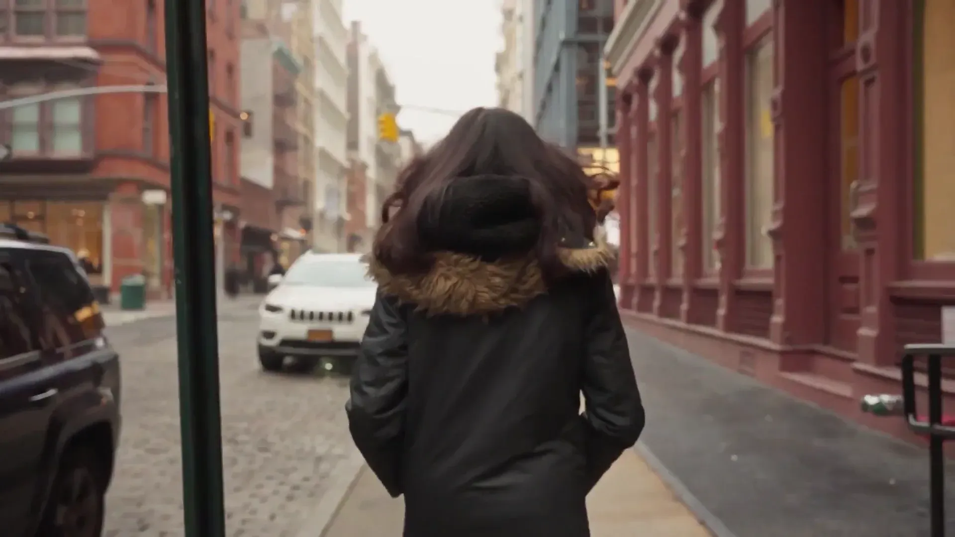 A still from the 'Build vs. buy: Why Anthropic chose Fin' video, showing a woman in a fur-hooded coat walking down a city street